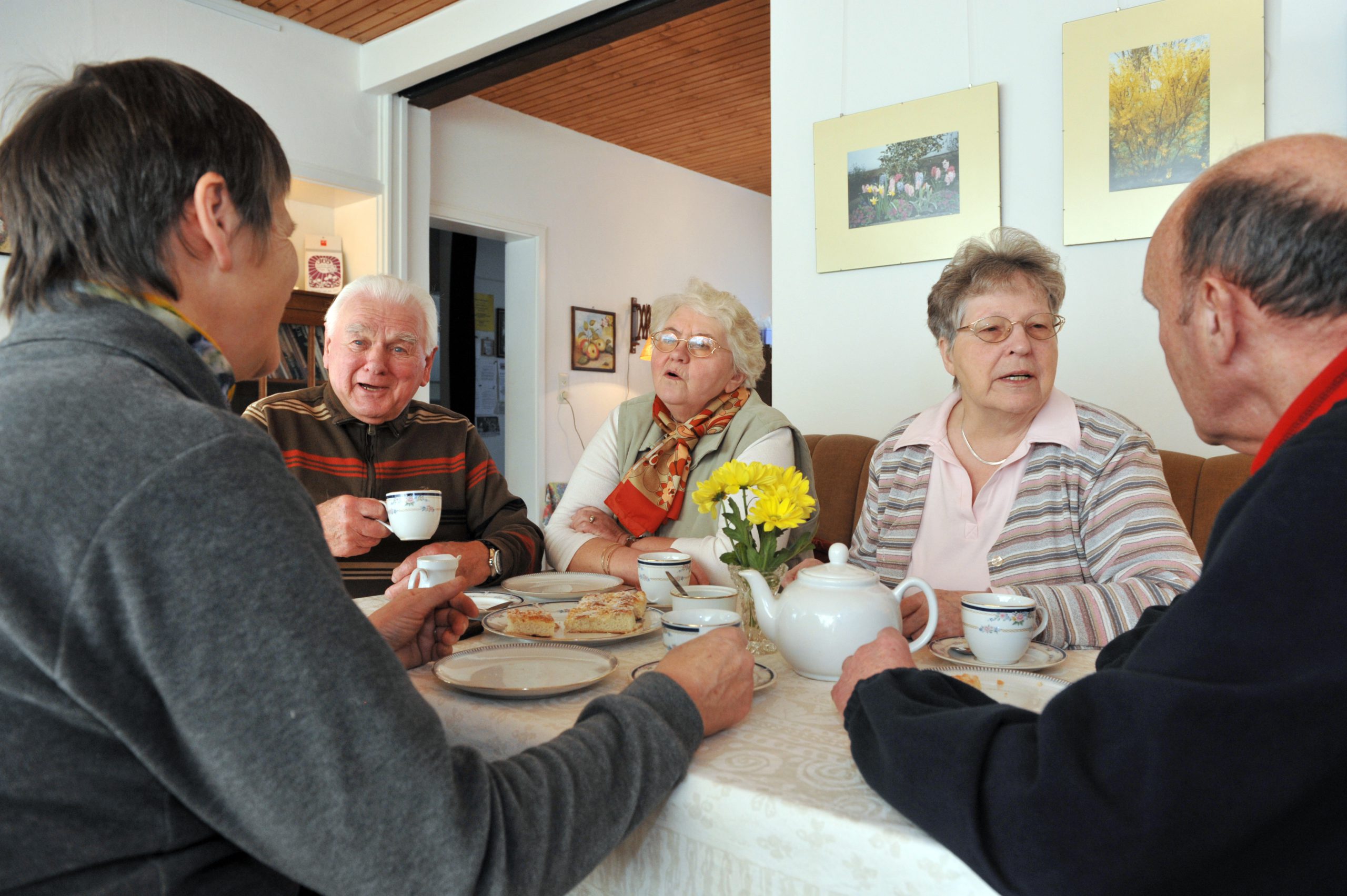Gemütliche Runde von Bewohnerinnen und Bewohnern mit Kaffee und Kuchen