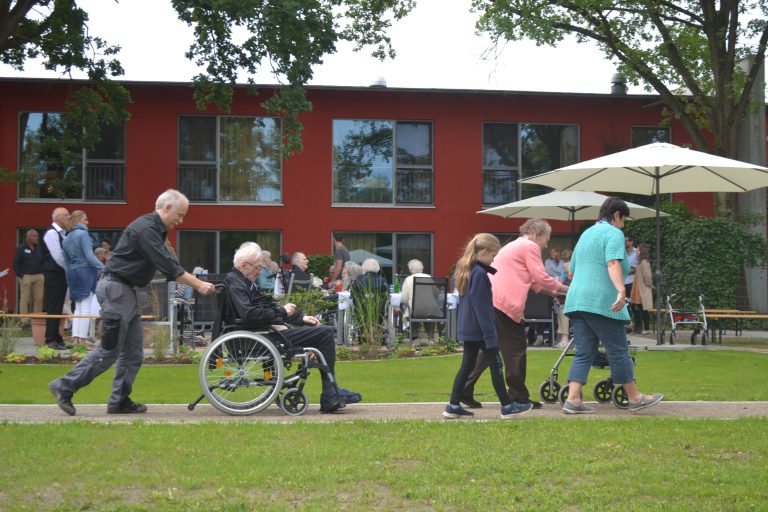 Viele Bewohnerinnen und Bewohner mit Angehörigen vor einem Pflegeheim